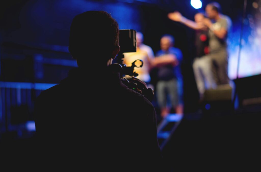 pexels-photo-1870438-1870438 Man Standing on Stage Holding Microphone