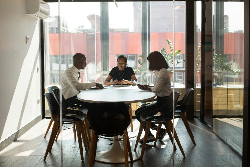 Three professionals collaborating in a modern office boardroom setting during daylight.